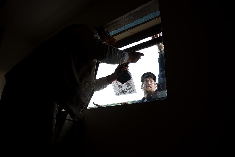 Rod Bean, left and Mark Stadtmiller of HOME Partners install a window in what will become office space for HP Roofing in White River Junction, Vt. on March, 24, 2015.  (Valley News - Jennifer Hauck) Copyright © Valley News. May not be reprinted or used online without permission. Send requests to permission@vnews.com. - Jennifer Hauck | Valley News