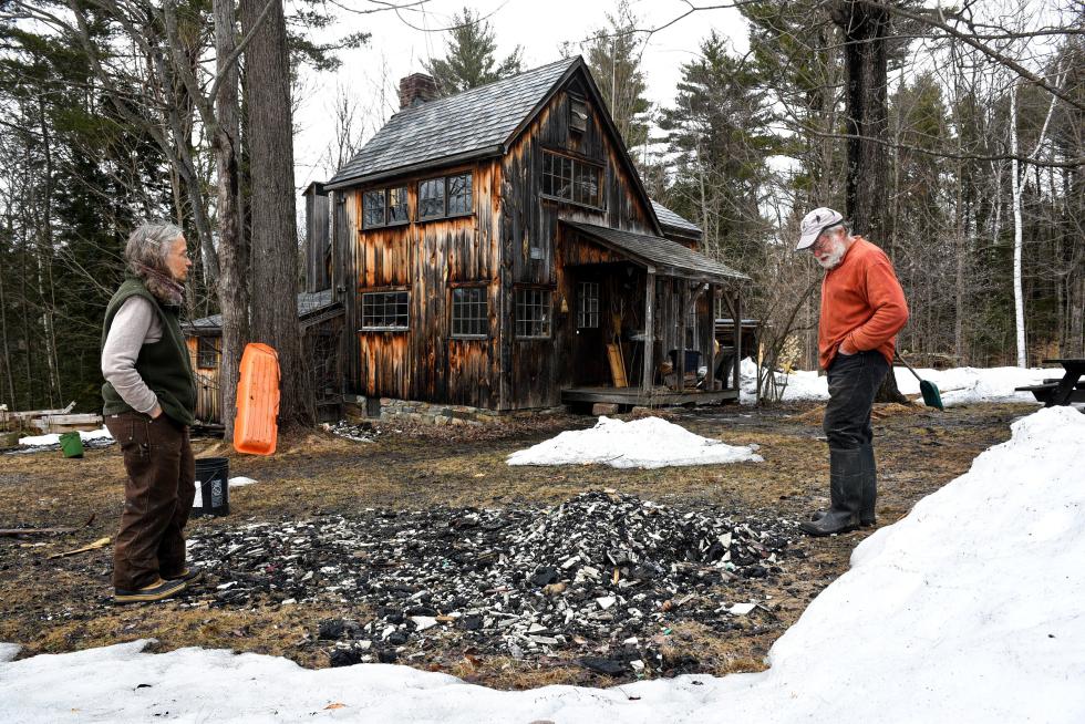 Jenny Wright and Stan McCumber stand over a pile of ash, coals and lath Friday, March 27, 2015 scraped out of their home after a fire started near their wood stove in February. Wright and McCumber built the home together in the late 1960's while living nearby in a 10 foot by 10 foot cabin. It was during this project that they discovered how well they work together. (Valley News - James M. Patterson) <p><i>Copyright Â© Valley News. May not be reprinted or used online without permission. Send requests to permission@vnews.com.</i></p> - James M. Patterson | Valley News