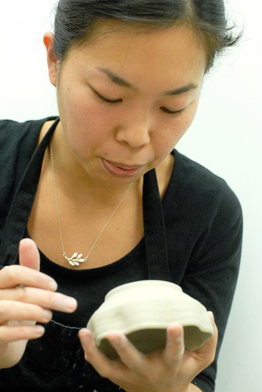 Sumire Kobayashi of Hanover blows away dust after signing the base of a bowl she made in a Japanese pottery class at the League of New Hampshire Craftsmen in Hanover. Valley News - James M. Patterson jpatterson@vnews.com photo@vnews.com - James M. Patterson | Valley News