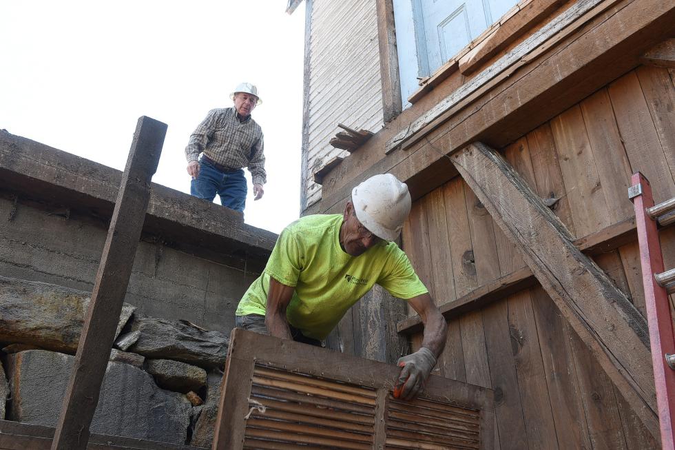 Gerry DeMuro, left, watches in anticipation as Russell Bishop, of Pine Hill Construction, installs doors on a100-year-old year old "bolter" used to grind grain in the basement of a former mill on Pleasant Street in Claremont, N.H., on May 6, 2015. (Valley News - Sarah Priestap) Copyright © Valley News. May not be reprinted or used online without permission. Send requests to permission@vnews.com. - Sarah Priestap | Valley News