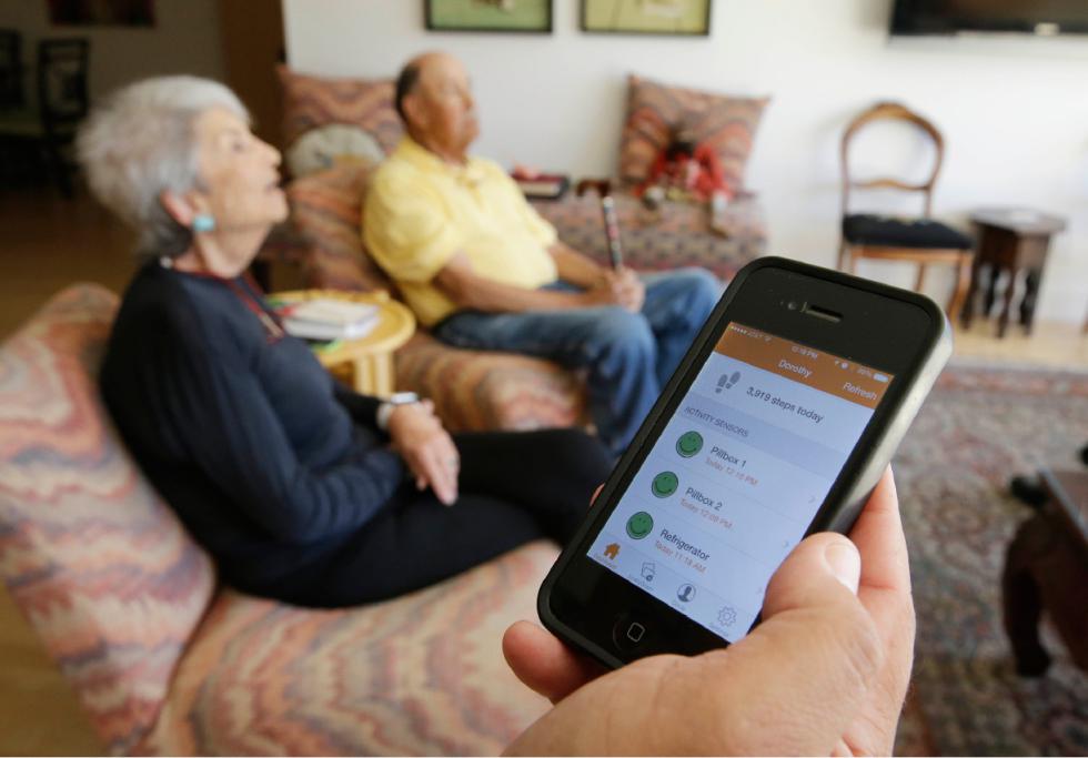 In this March 17, 2015 photo, Phil Dworsky shows off an app on his phone that displays the movements of his parents, Dorothy, 80, left, and Bill Dworsky, 81, rear, at their home in San Francisco. Each time an elder Dworksy opens the refrigerator, closes the bathroom door or lifts the lid on a pill container, tiny sensors in their home make notes on a digital logbook, which the younger Dworsky monitors daily on his smartphone. (AP Photo/Eric Risberg) - Eric Risberg | AP