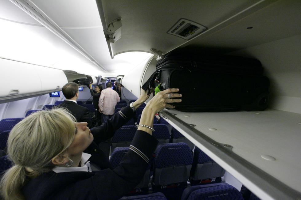 FILE - In this April 13, 2009 file photo, American Airlines flight attendant Renee Schexnaildre demonstrates the overhead baggage area during a media preview of the airline's new Boeing 737-800 jets, at Dallas Fort Worth International Airport in Grapevine, Texas. Global airlines on Tuesday, June 9, 2015 announced new guidelines that would shrink the size of bags allowed on planes, part of an effort to free up space in packed overhead bins. (AP Photo/Donna McWilliam, File) - Donna McWilliam | AP