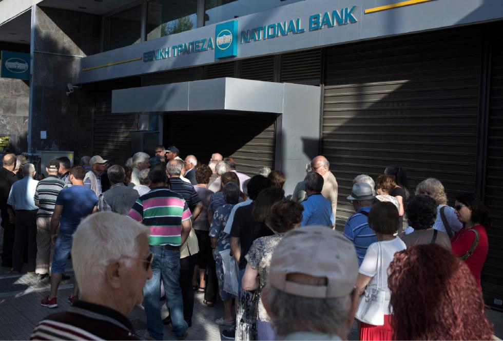 Elderly people, who usually get their pensions at the end of the month, wait outside a closed bank in Athens, Monday, June 29, 2015. Greece's five-year financial crisis took its most dramatic turn yet, with the cabinet deciding that Greek banks would remain shut for six business days and restrictions would be imposed on cash withdrawals. (AP Photo/Petros Giannakouris) - Petros Giannakouris | AP