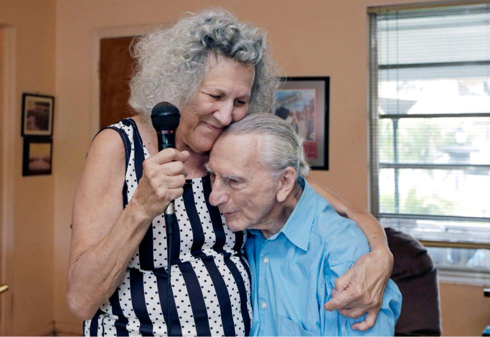 In this May 11, 2015 photo, Saundra Karp hugs her husband, Al, after a rehearsal at their home in North Miami Beach, Fla. The Karps, along with their son, Larry, perform old standards locally as the Karp Family band to ease stress and help raise money to save their home from foreclosure. (AP Photo/Alan Diaz) - Alan Diaz | AP
