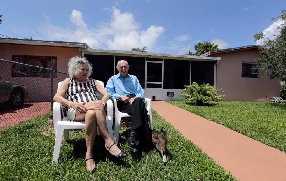 In this May 11, 2015 photo, Al Karp, right, and wife Saundra, pose in front of their home in North Miami Beach, Fla. The Karps, along with their son, Larry, perform old standards locally as the Karp Family band to ease stress and help raise money to save their home from foreclosure. (AP Photo/Alan Diaz) - Alan Diaz | AP