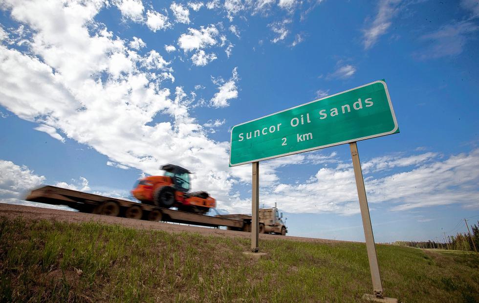A truck drives past a Suncor Energy Inc. Energy Inc. oil sands road sign near Fort McMurray, Alberta, Canada.The era of the megaproject in Canadas oil sands is fading as crudes price slump, pressure to get off fossil fuels and tax increases in Alberta are prompting producers from Suncor Energy Inc. to Imperial Oil Ltd. to accelerate a shift to smaller projects. Illustrates OIL-CANADA (category f) by Rebecca Penty and Jeremy Van Loon (c) 2015, Bloomberg News. Moved Thursday, June 18, 2015 (MUST CREDIT: Bloomberg News photo by Ben Nelms). - NELMS | BLOOMBERG NEWS