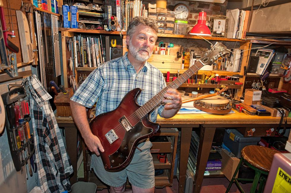Will Morneault with his favorite guitar, "Stinky Jr.," named for another guitar, "Stinky," which had a bad smell from the red lacquer someone had applied to hide fire damage. The lacquer never cured correctly. Medora Hebert photograph -