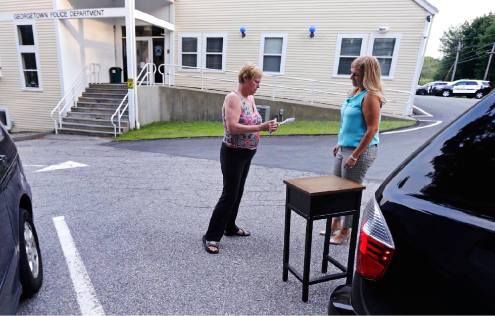 Susan Locke, left, counts out her cash as she purchases a table  from Michele Velleman in the "online safe zone" outside the police station in Georgetown, Mass., Monday, July 13, 2015. Around the nation, in police department parking lots festooned with surveillance cameras, authorities are setting up an "online safe zones" where people meeting via Craigslist or buying goods via eBay can encounter each other without fear of assault or abduction. (AP Photo/Charles Krupa) - Charles Krupa | AP
