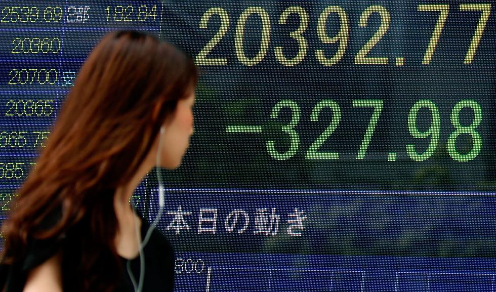 A woman walks past an electronic stock indicator of a securities firm in Tokyo, displaying Tokyoâs Nikkei 225 that lost 327.98 points or 1.58 percent to 20,392.77, Wednesday, Aug. 12, 2015. Asian stocks sank as China let its currency fall for a second day following a surprise devaluation that rattled global financial markets. (AP Photo/Ken Aragaki) - Ken Aragaki | AP
