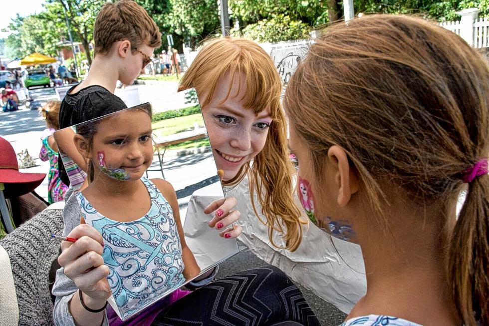 Lucia Peraza, 6, of Hanover checks out the mermaid painted on her face by Charlotte Atkinson, of Strafford, at the ArtisTree booth during The Taste of Woodstock festival on Aug. 8. Nancy Nutile-McMenemy photograph -
