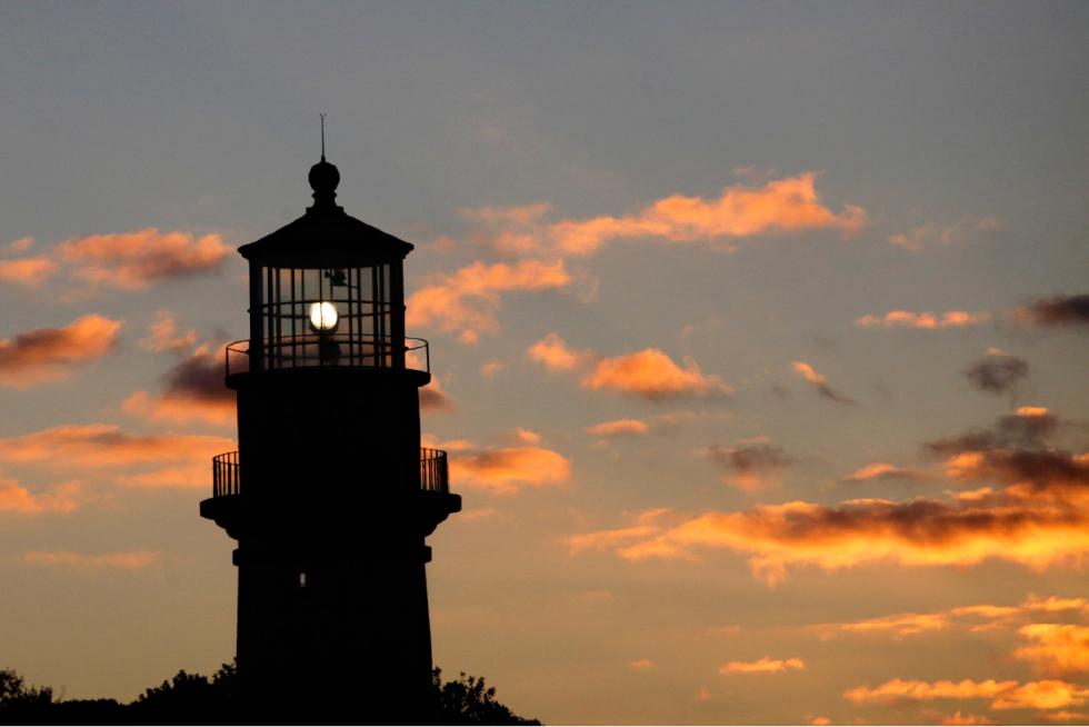 FILE - In this Oct. 13, 2013 file photo, Gay Head Light flashes a white signal in Aquinnah, Mass., on the island of Martha's Vineyard. The lighthouse flashes alternating red and white beams of light. The 160-year-old lighthouse was powered down and began a slow trek on rails in May 2015 to a new home about 135 feet further inland, away from a rapidly-eroding cliffside. A re-lighting ceremony is scheduled for Tuesday, Aug. 11, 2015, after lighthouse was anchored at its new location. (AP Photo/Mark Lennihan, File) - Mark Lennihan | AP