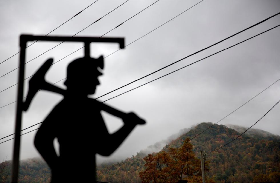 FILE - In this Oct. 16, 2014 file photo, fog hovers over a mountaintop as a cutout depicting a coal miner stands at a memorial to local miners killed on the job in Cumberland, Ky. Kentucky coal miners bled and died to unionize. The union era's death knell sounded in Kentucky on Dec. 31, 2014, when Patriot Coal announced the closing of its Highland Mine. (AP Photo/David Goldman, File) - David Goldman | AP