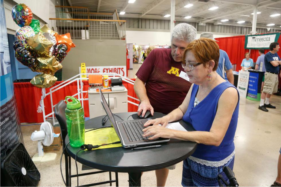ADVANCE FOR USE SUNDAY, OCT. 18, 2015 AND THEREAFTER - In this June 2, 2015 photo, State Rep. Joe Atkins helps Gayle Wyant, right, check her name in the Minnesotas Department of Commerce unclaimed property list at a booth at the Minnesota State Fair in Falcon Heights, Minn. Atkins said he stumbled on the issue in the fall of 2014 when a friend mentioned the state had taken control of $700 belonging to his grandmother. Like other unclaimed property, it went directly to the state's general fund. Atkins decided to search the state's unclaimed assets list for people in his district. In three weeks, working 10 minutes a day, Atkins said he easily located people holding claims for $309,363. "These are people I see at the grocery store. They're not hard to find. They live down the street from me," Atkins said. (AP Photo/Jim Mone) - Jim Mone | AP