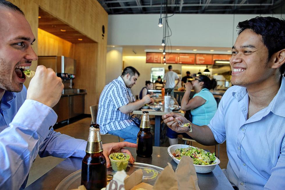 Tom Smurr, 24, and Charlie Chan, 27, from left, enjoy lunch at a Chipotle in Chicago. (Michael Tercha/Chicago Tribune/TNS) - Michael Tercha | Chicago Tribune