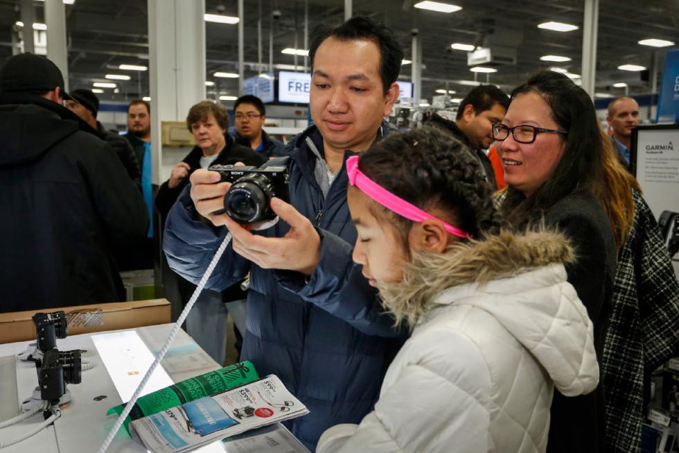 Koko Htwe looks at a camera at Best Buy with Sandy Htwe, center, and Nyo Nyo Soe on Thursday, Nov. 26, 2015, in Minnetonka, Minn. Early numbers arent out yet on how many shoppers headed to stores on Thanksgiving, but its expected that more than three times the number of people will venture out to shop on the day after the holiday known as Black Friday. (AP Photo/Bruce Kluckhohn) - Bruce Kluckhohn | FR170893 AP