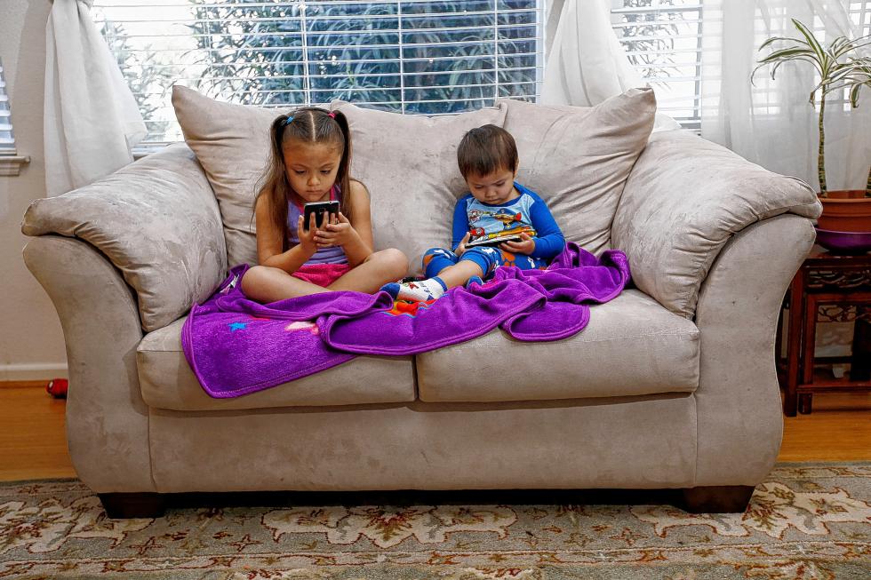 Juliana Sanchez, 5, and her brother, Francisco Sanchez Jr., 2, watch children's programming on YouTube on their parent's cell phones at their home on March 9, 2015 in Mountain House, Calif. Watching digital video on hand-held devices is the new normal for tots, tweens and teens. (Gary Reyes/Bay Area News Group/TNS) - Gary Reyes | San Jose Mercury News