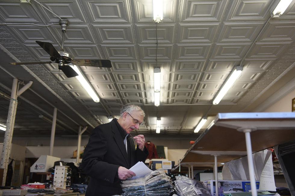 Ed Hirsch, third-generation owner of Hirsch's Clothing in Lebanon, N.H., checks an embroidery order for name accuracy in the front of the store on Jan. 7, 2015. Hirsch, who took over the store in the early eighties when a relative unexpectedly died, says he fills many custom orders that include embroidery for local businesses and fire departments.  (Valley News - Sarah Priestap) Copyright © Valley News. May not be reprinted or used online without permission. Send requests to permission@vnews.com. - Sarah Priestap | Valley News
