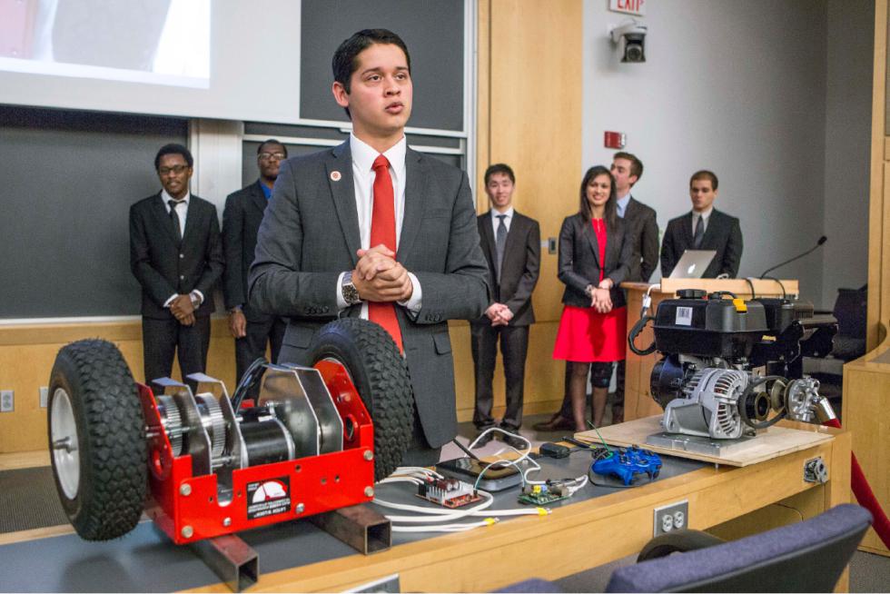 In this December 2015 photo provided by Harvard University, junior Cesar Maeda explains a robotic snow blower to a group of officials at Harvard in Cambridge, Mass. Eighteen juniors representing several engineering disciplines spent the fall semester inventing a robotic remote-control rooftop snowblower, a super-heated icicle cutter and a freeze-resistant doormat. The inventions grew out of last winters record snowfall, which stretched campus maintenance department workers to their limit and forced a campus shutdown for the first time since the Blizzard of 78. (Photo by Eliza Grinnell/Harvard University John A. Paulson School of Engineering and Applied Sciences via AP) - Eliza Grinnell | Harvard University John A. Pauls