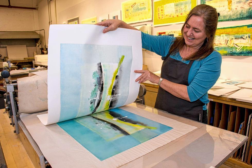 After soaking paper, monotype printmaker Patti Castellini places it on top of her design then rolls the print "sandwich" through the press. She slowly peels the paper off the image, hangs it to dry and eventually will frame it. Castellini rents space at the Two Rivers Printmaking Studio in White River Junction. She also maintains a studio in her home but prefers the openness and space afforded by Two Rivers. (Nancy Nutile-McMenemy photograph/www.photosbynanci.com) -
