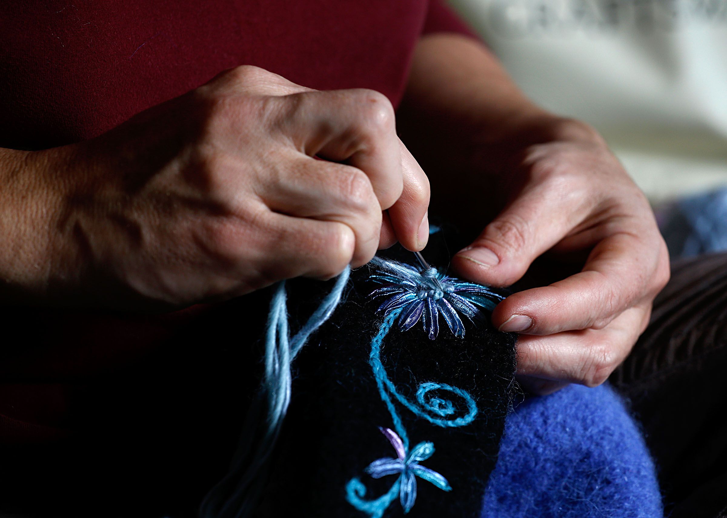 : Artistic StitchesCarrie Cahill Mulligan embroiders a floral design on the front of one of her hand-knit hats at her home studio in Canaan. Mulligan moved to Canaan from Alaska in 2004.