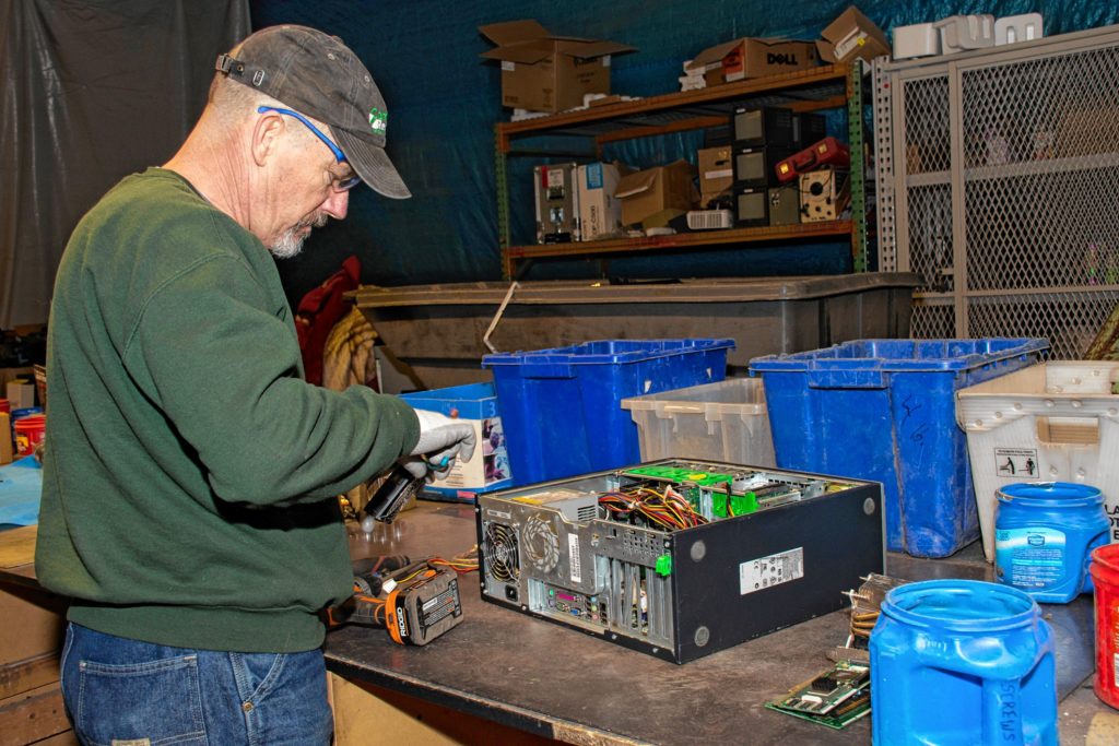 Left: Computer Recycling of Claremont owner Ken Burke disassembles a computer tower. Above: President Mark Glassberg shows off a newly refurbished computer that is  available for purchase at WinCycle. The nonprofit  also provides computers to other nonprofits, small businesses, and low-income residents.