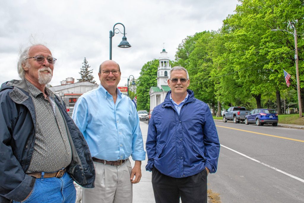Bob Haight (left), Tom Marsh (center) and John Tansey (right) of Distinctly Windsor stand on one of the town's recent infrastructure projects along Main Street, a new sidewalk and railing. Nancy Nutile-McMenemy photograph.