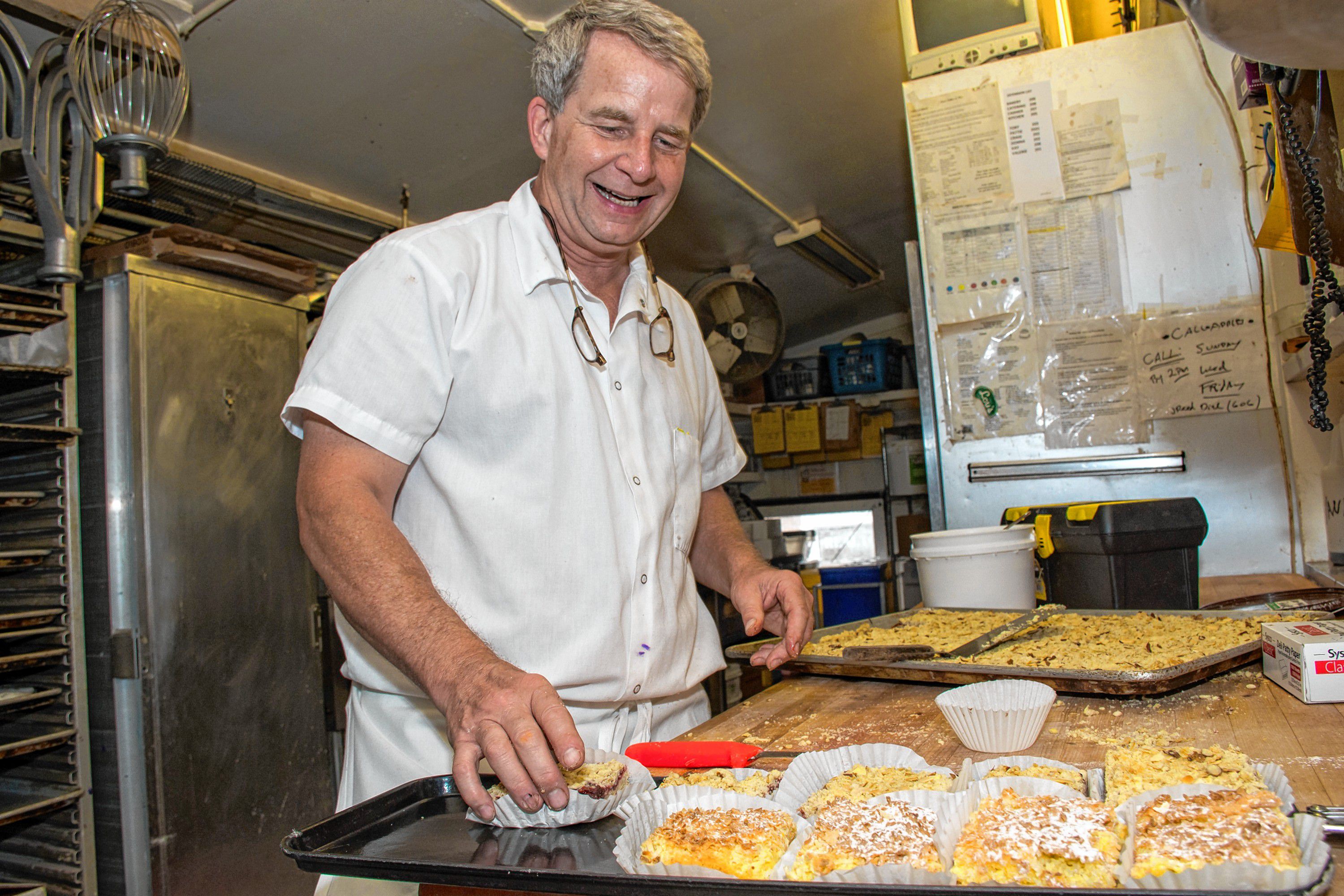 For 25 years, Toby Fried has baked in the back room "bakery." He knows what to make for tourists and what to make for Dartmouth College Students. Here he's cutting up raspberry almond squares to add to the tray of lemon squares. "The students don't go much for the lemon coconut squares but the tourists do." Nancy Nutile-McMenemy photograph.