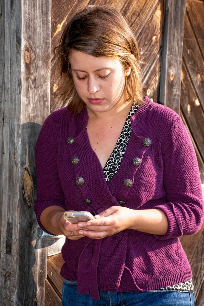 After taking care of the sheep, Sarah Danly, network manager for Vermont's Farm to Plate food system plan, checks her phone before driving to her office in Montpelier, Vt. (Nancy Nutile-McMenemy photograph)