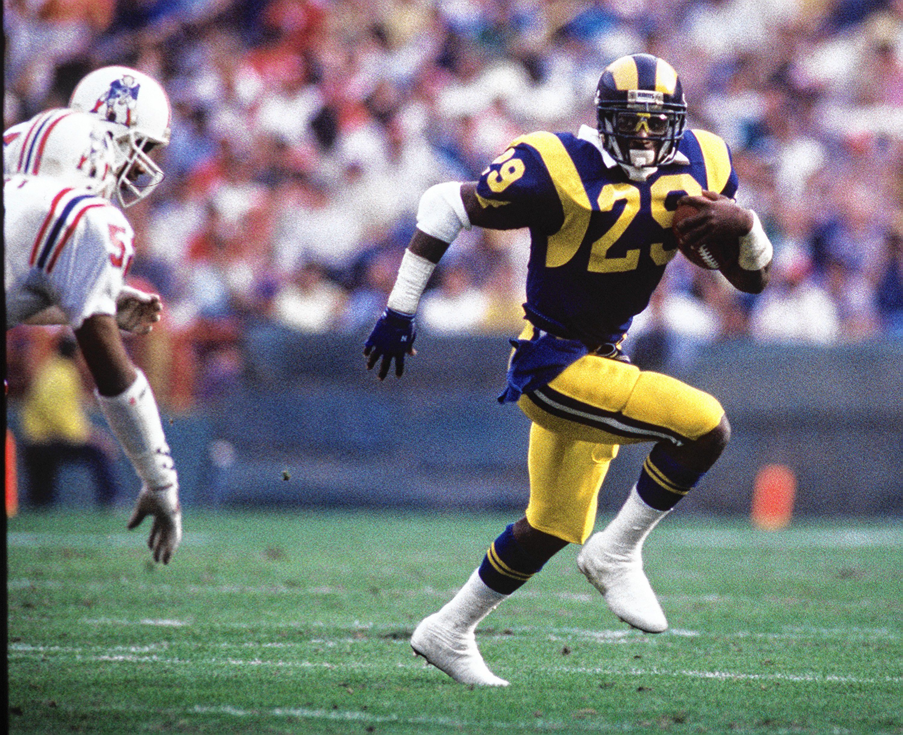 Eric Dickerson carries the ball against members of the New England Patriots defense in this file photo. (Christine Cotter/Los Angeles Times/TNS)