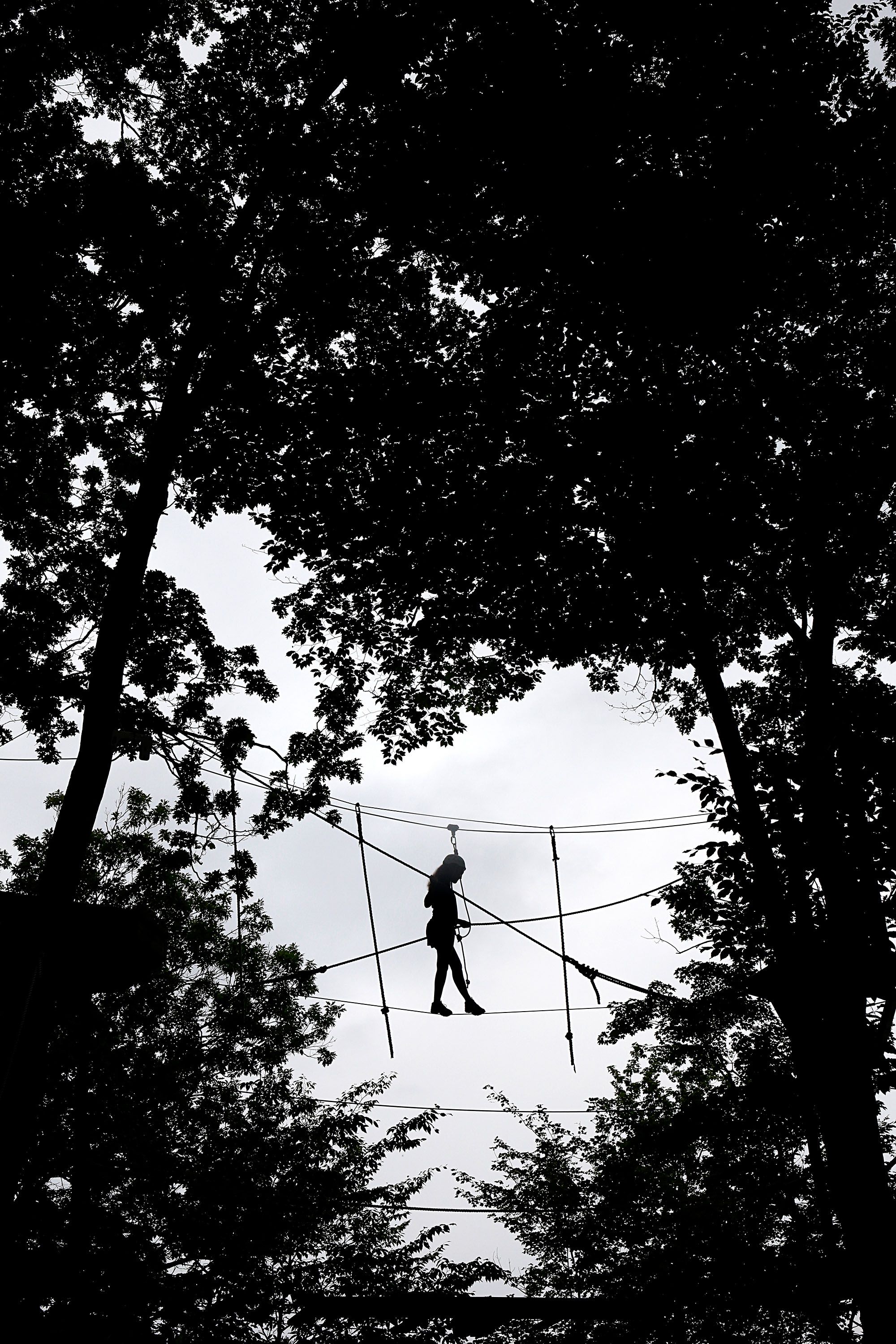 While buckled in with a harness, Molly Flaherty, 15, of Foxborough, Mass., watches her step as she negotiates a tightrope at  the Aerial Challenge Course at Mount Sunapee Resort's Adventure Park in Sunapee, N.H., on July 14, 2018. The resort has added several recreational activities, including the course, to become a year-round destination. (Valley News - Geoff Hansen) Copyright Valley News. May not be reprinted or used online without permission. Send requests to permission@vnews.com.
