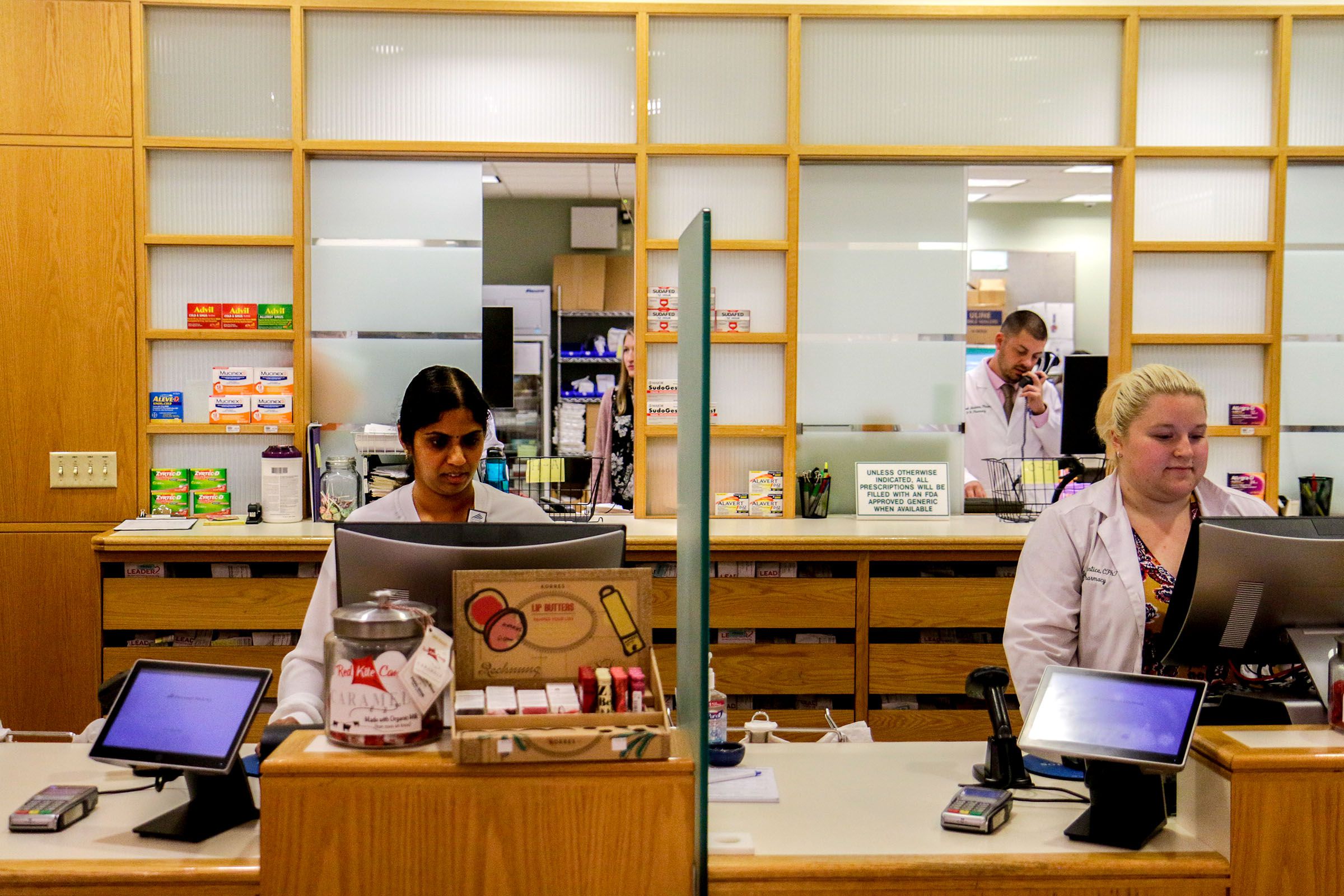 Pharmacy Technicians Vijaya Modugula, left, of Hanover, N.H., Jessica Prentice, of Lebanon, N.H., and pharmacist Michael Nardone, back, of Manchester, N.H., work in the outpatient pharmacy of Dartmouth-Hitchcock Medical Center in Lebanon, N.H., on Tuesday, Oct. 9, 2018. Modugula recently began her apprenticeship in the DHMC's Workforce Readiness Institute program after completing a nine-week training. She plans to continue as a pharmacy technician after completing the apprenticeship. (Valley News - August Frank) Copyright Valley News. May not be reprinted or used online without permission. Send requests to permission@vnews.com.