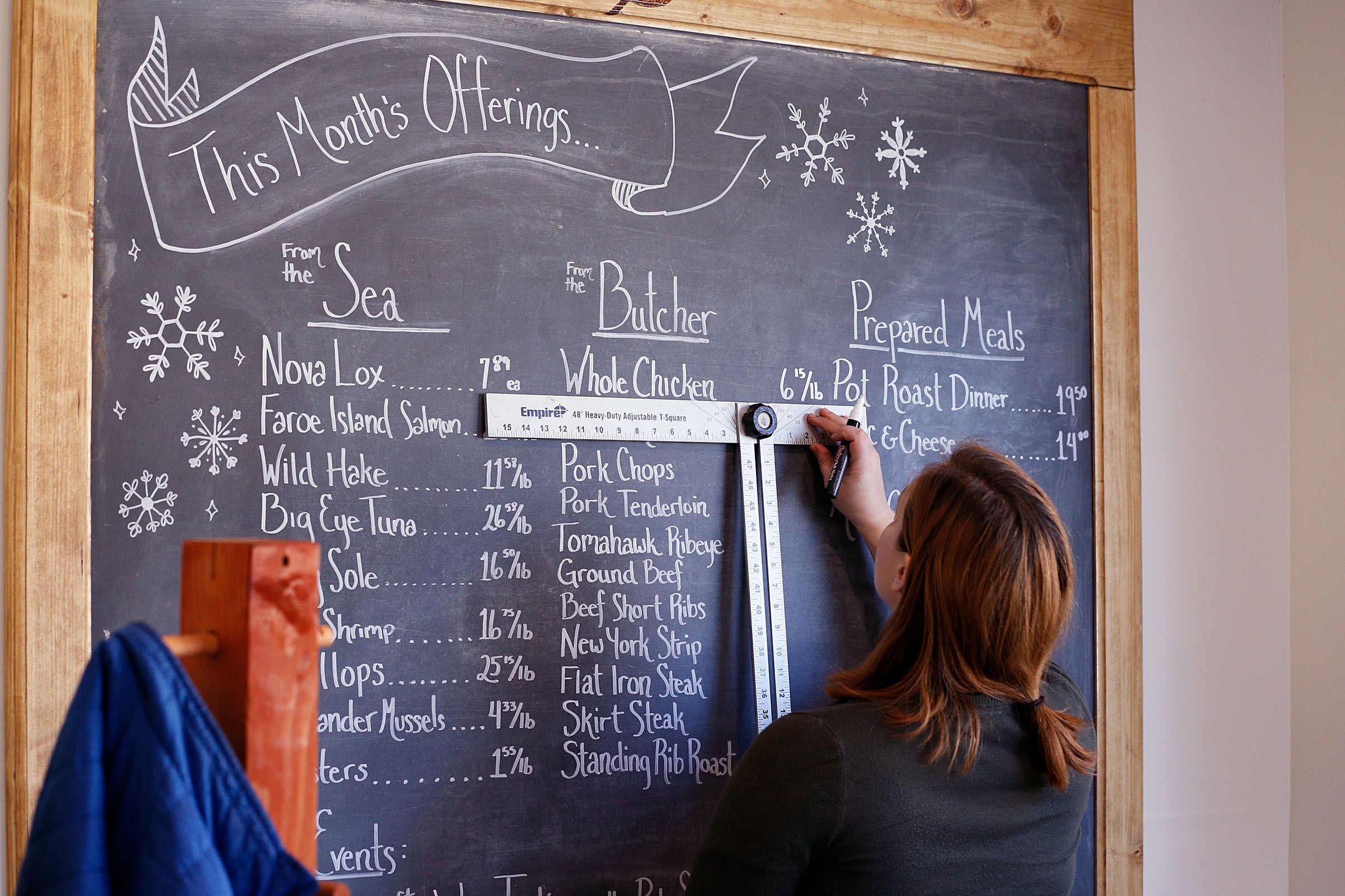 Assistant director of food and beverage Carrie Swain, of North Hartland, Vt., fills out the board at the Brownsville Butcher & Pantry in Brownsville, Vt., on Jan. 17, 2019. "I love the community and all of the people who have been welcoming us," Swain said. (Valley News - Joseph Ressler) Copyright Valley News. May not be reprinted or used online without permission. Send requests to permission@vnews.com.