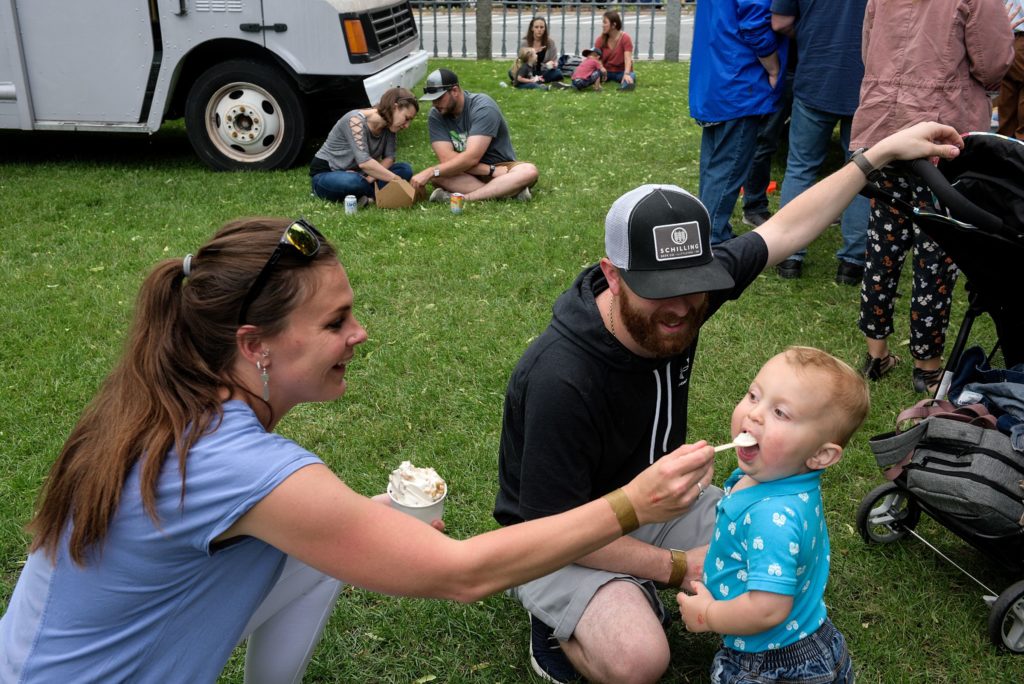 Colin Maville, 1, of Enfield, gets a bite of Mac's Sugarhouse maple creamee from his mother Kara as his father Beau looks on at the Lebanon (N.H.) Food Truck Festival in Colburn Park, Friday, June 21, 2019. Funds raised from ticket sales benefit the city's park development. (Valley News - James M. Patterson) Copyright Valley News. May not be reprinted or used online without permission. Send requests to permission@vnews.com.