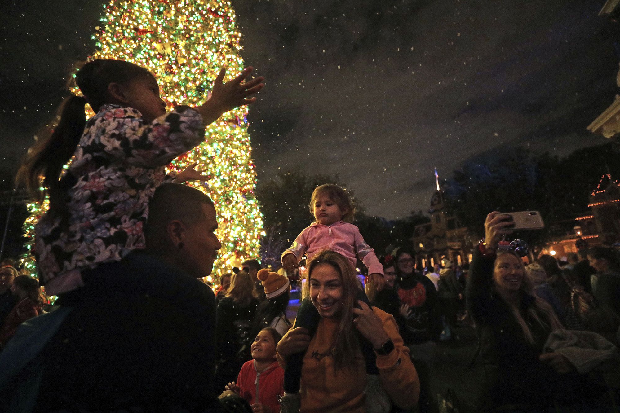 Tino Liquigan, left, and wife Raquel with their daughters amid the falling 'snow' on Disneyland's Main Street on Nov. 21, 2019 in Anaheim, Calif. (Myung J. Chun/Los Angeles Times/TNS)
