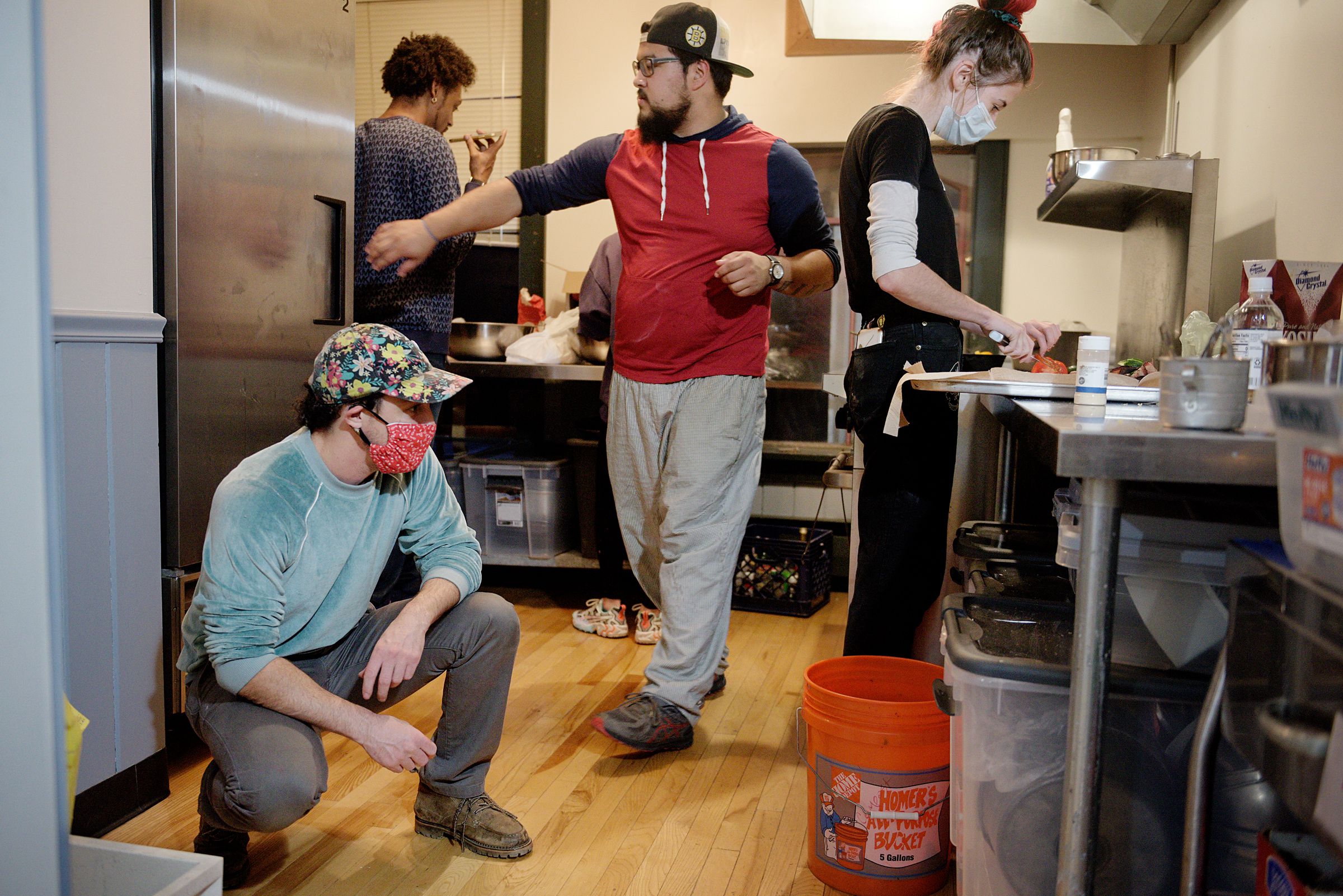 Jesse Plotsky, co-owner of Babes Bar, left, looks for a cake pan as Tre Groves, top left, Tristan Brown, middle, and Grace Dorman, right, prepare a meal at the Arnold Block test kitchen in Bethel, Vt., Wednesday, Oct. 8, 2020. The group is developing a menu for a food trailer they are preparing to open with Babes as the parent business. “I am not remarkable in any particular way,” said Plotsky about his activism. “I see my role as the holder of space. I’m basically here to do what is asked of me, knowing the power that I hold as a business owner and as a white person.” (Valley News - James M. Patterson) Copyright Valley News. May not be reprinted or used online without permission. Send requests to permission@vnews.com.
