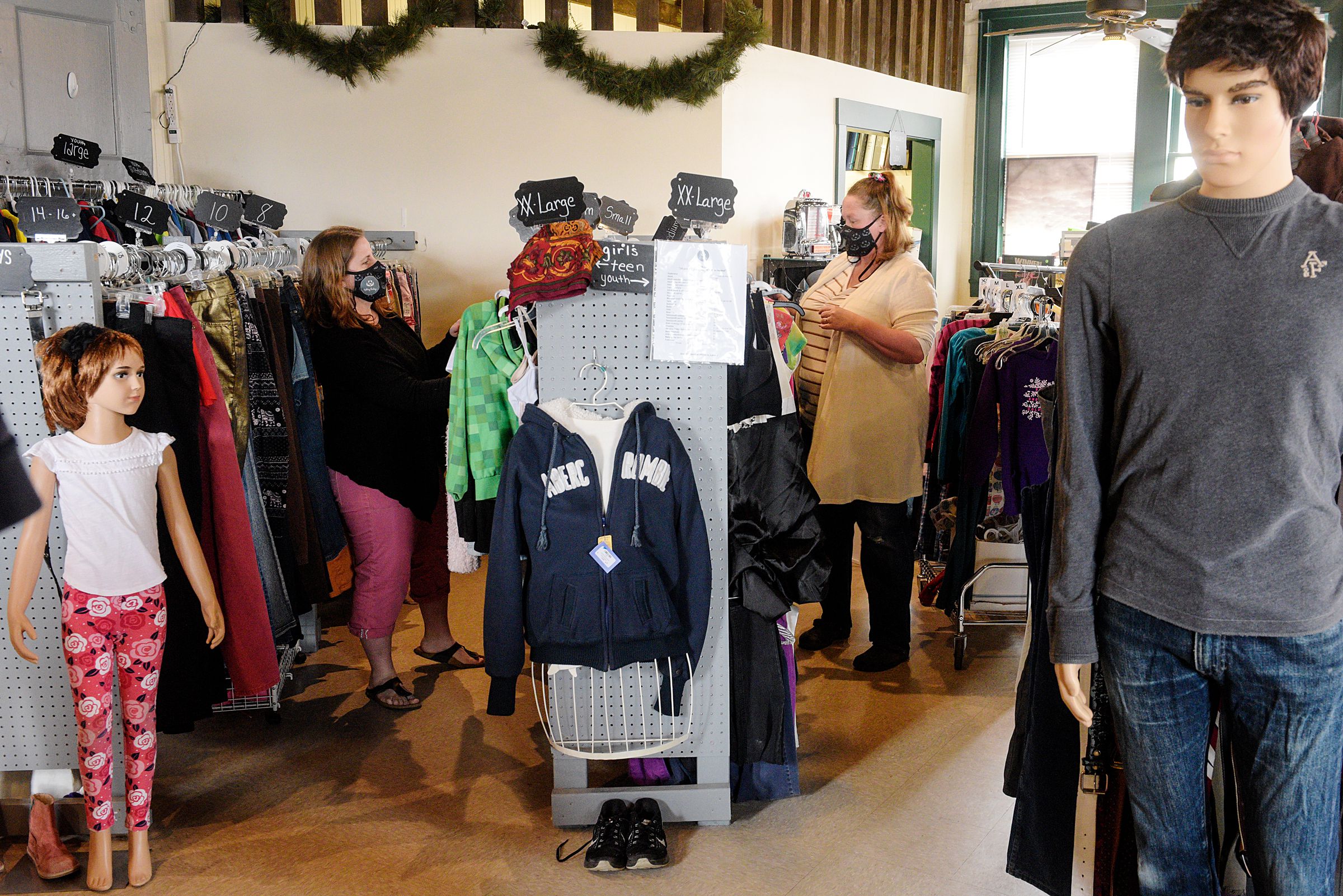 Gail Egner, owner of Uplifting Thrifting, left, and Jaime Neily, right, rotate inventory on the racks at the store in White River Junction, Vt., Thursday, March 25, 2021. A year and three months after opening in the White River Junction train station, Egner has weathered the worst of the pandemic with curbside service, opened the business to some consignment, and continues efforts to serve families suffering after house fires. (Valley News - James M. Patterson) Copyright Valley News. May not be reprinted or used online without permission. Send requests to permission@vnews.com.