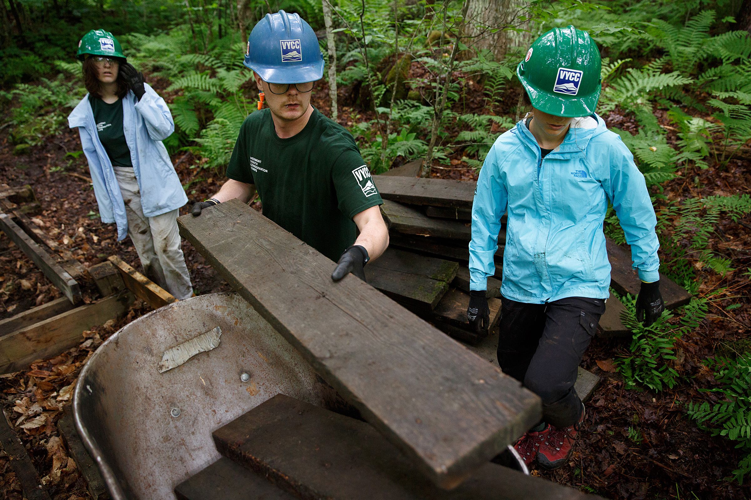 From left, Beatrix Garza, 15, of Woodstock, Vt., conservation crew leader Sawyer Connolly, of Enfield, N.H., and Chloe Masillo, 15, of Pittsfield, Vt., with Vermont Youth Conservation Corps replace a footbridge near the Prosper Trail trailhead at Marsh-Billings-Rockefeller National Historic Park in Woodstock, Vt., on Tuesday, June 22, 2021. The crew is tearing out the decaying boards and replacing them with pressure-treated wood. (Valley News / Report For America - Alex Driehaus) Copyright Valley News. May not be reprinted or used online without permission. Send requests to permission@vnews.com.