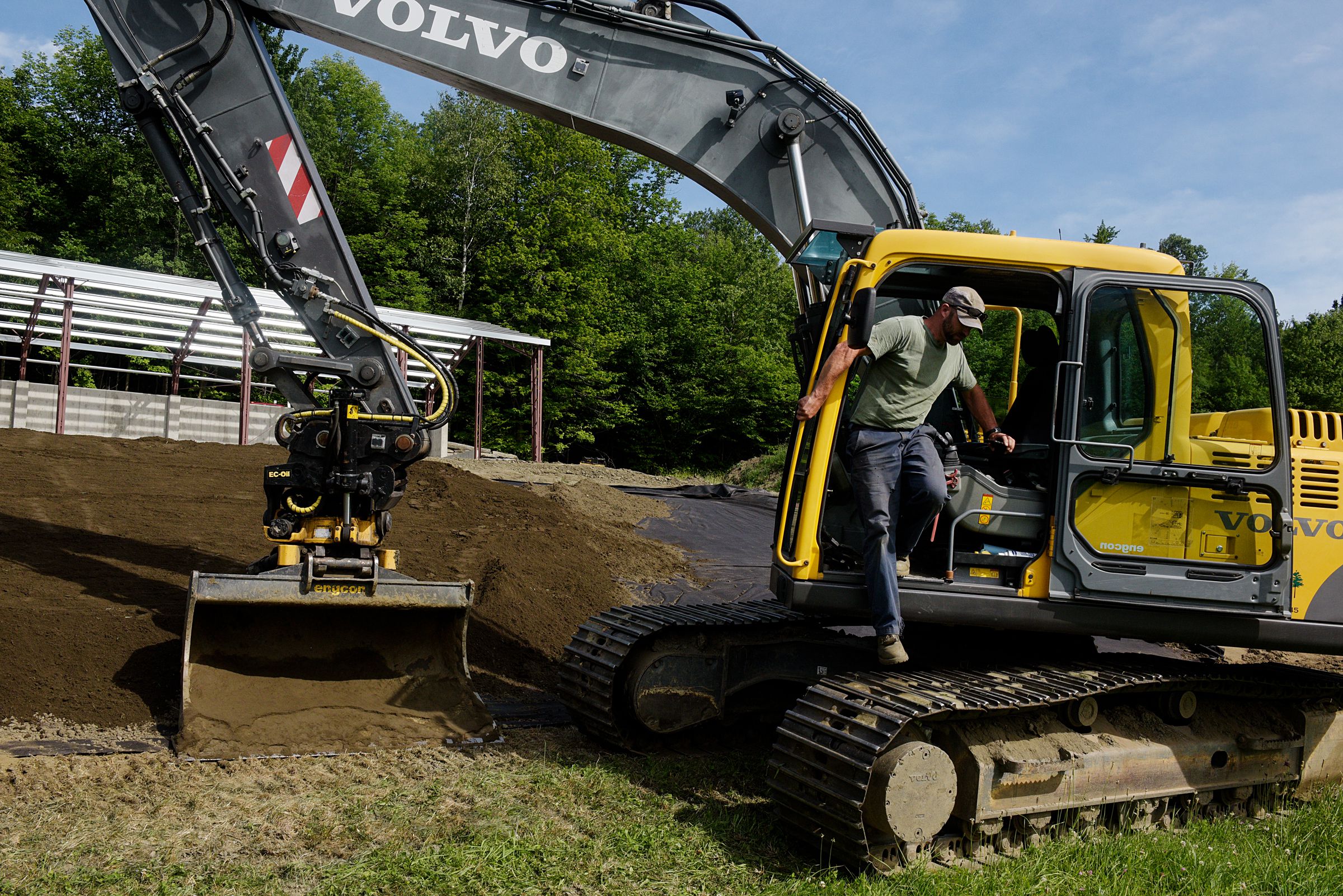 Ben Canonica, of Chelsea, steps down from his excavator after spreading a layer of topsoil on a septic system he is building as part of a new home for a client in Tunbridge, Vt., Friday, June 25, 2021. (Valley News - James M. Patterson) Copyright Valley News. May not be reprinted or used online without permission. Send requests to permission@vnews.com.