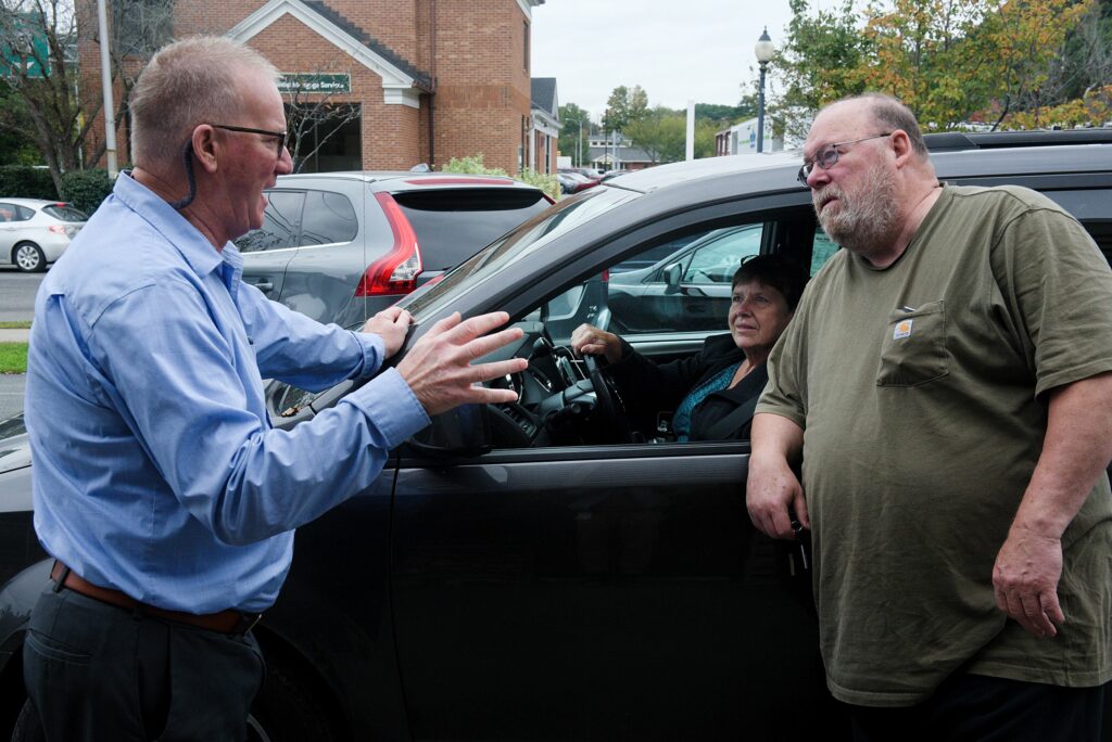 Brad Gilman, left, talks to Joan Smith, of Norwich, middle, and her partner Lincoln Robtoy, right, after handing over the key to a truck they bought at Upper Valley Auto Mart, where Gilman is general manager in White River Junction, Vt., on Monday, Oct. 4, 2021. Smith and Robtoy purchased their last two vehicles from the used car dealership.  (Valley News - James M. Patterson) Copyright Valley News.  May not be reprinted or used online without permission.  Send your requests to permission@vnews.com.