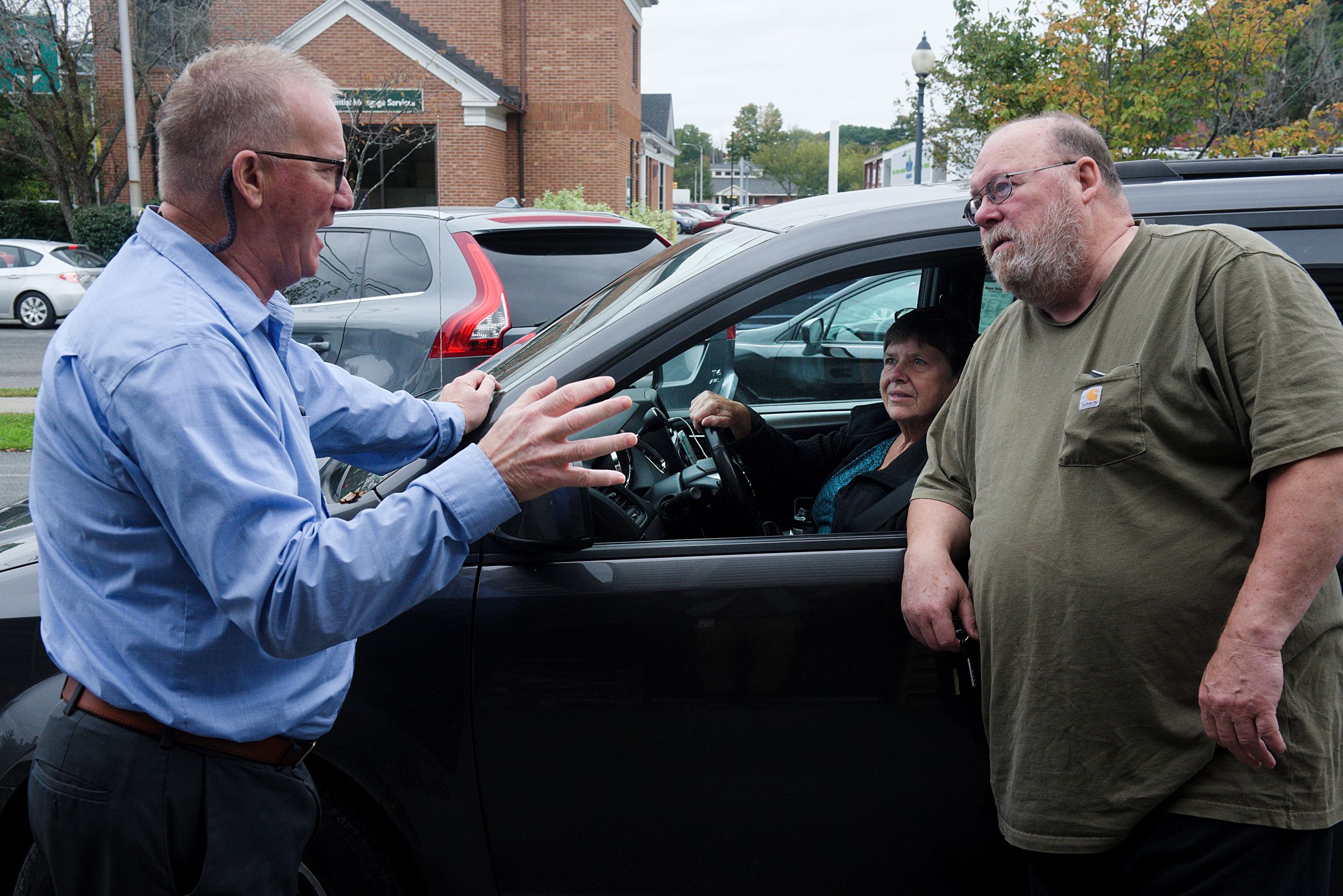 Brad Gilman, left, talks with Joan Smith, of Norwich, middle, and her partner Lincoln Robtoy, right, after handing over the key to a truck they bought at Upper Valley Auto Mart, where Gilman is general manager in White River Junction, Vt., on Monday, Oct. 4, 2021. Smith and Robtoy have purchased their last two vehicles from the used auto dealer. (Valley News - James M. Patterson) Copyright Valley News. May not be reprinted or used online without permission. Send requests to permission@vnews.com.