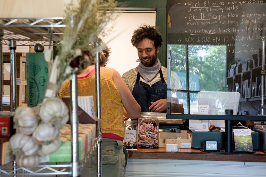 Misha Johnson, right, sells a coffee to Trudy Amber, of Chelsea, at the Free Verse Farm store in Chelsea, Vt., on Tuesday, June 28, 2022. The store also sells a line of their own body care products alongside other locally made bath and body products. (Valley News - James M. Patterson) Copyright Valley News. May not be reprinted or used online without permission. Send requests to permission@vnews.com.