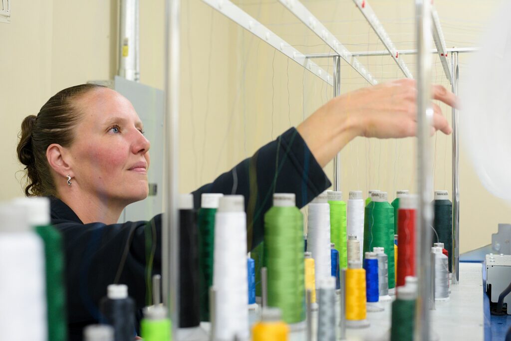 Amanda McKinney sets up a fresh spool of thread in an embroidery machine at Top Stitch Embroidery Lebanon, N.H., on Tuesday, Sept. 27, 2022. (Valley News - James M. Patterson) Copyright Valley News. May not be reprinted or used online without permission. Send requests to permission@vnews.com.