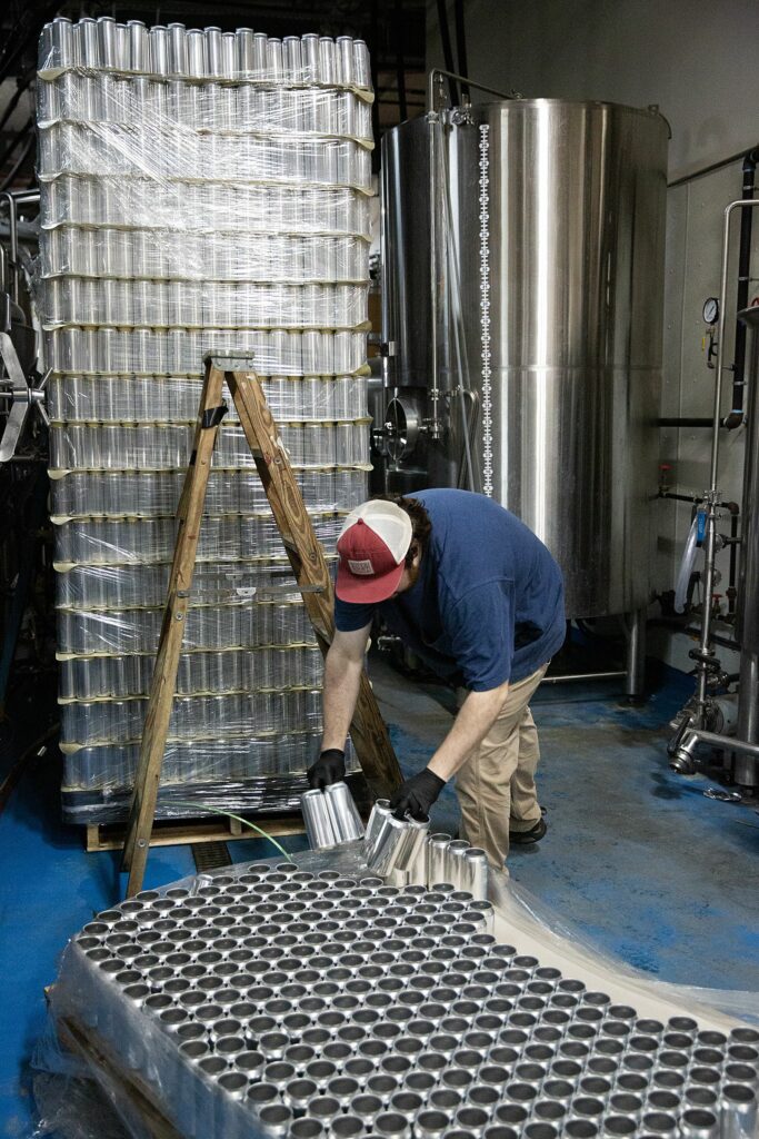 Edwin Royce picks up cans to be filled with Más Verde, an IPA beer made with citra and chinook hops, at River Roost Brewery in White River Junction, Vt., on Tuesday, March 28, 2023. (Valley News / Report For America - Alex Driehaus) Copyright Valley News. May not be reprinted or used online without permission. Send requests to permission@vnews.com.
